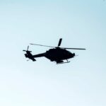 Silhouette of a helicopter flying against a light sky