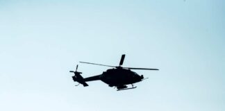 Silhouette of a helicopter flying against a light sky