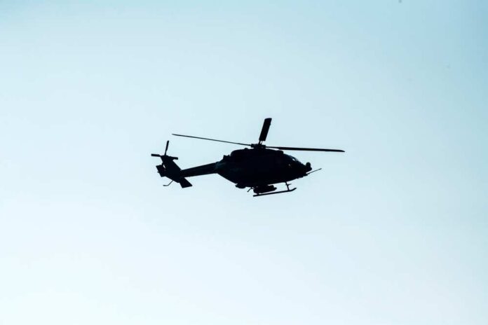 Silhouette of a helicopter flying against a light sky