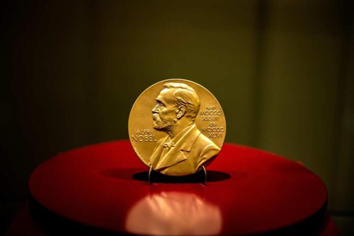 A gold Nobel Prize medal displayed on a red pedestal