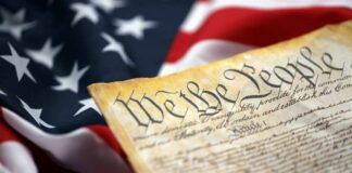 Close-up of a historical document with the American flag in the background