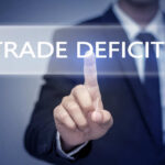 Business professional pointing at the phrase 'Trade Deficit' on a digital display