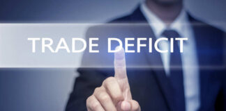 Business professional pointing at the phrase 'Trade Deficit' on a digital display