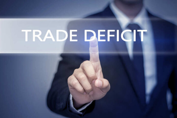 shutterstock_446043025.jpg Business professional pointing at the phrase 'Trade Deficit' on a digital display