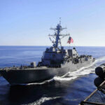 U.S. Navy F-35 BLASTS Iranian Drone Near Carrier Warship with American flag sailing in the ocean.