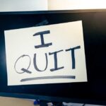 A computer monitor displaying a handwritten note that says 'I QUIT'
