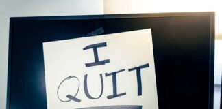 A computer monitor displaying a handwritten note that says 'I QUIT'