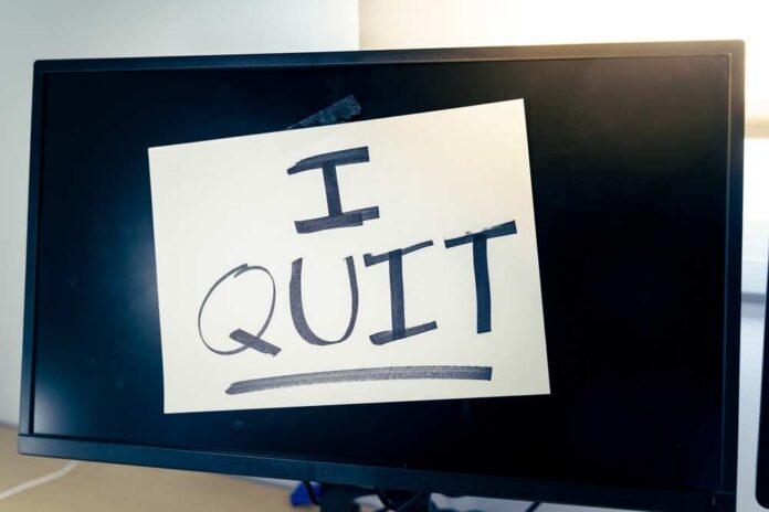 A computer monitor displaying a handwritten note that says 'I QUIT'
