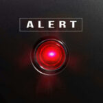 Red alert light against black background, text ALERT.