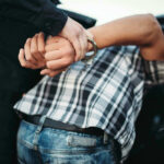 Person in handcuffs arrested by police officer.