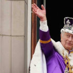 Man in royal attire and crown waving, stone background.