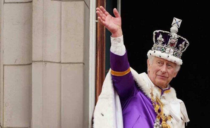 Man in royal attire and crown waving, stone background.