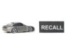 A miniature gray sports car next to a black sign that reads 'RECALL'