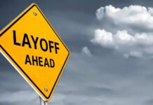 Yellow warning sign indicating layoffs ahead against a cloudy background