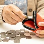Elderly person placing a coin into a red coin purse