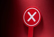 Red sign with a white cross symbol on a dark background