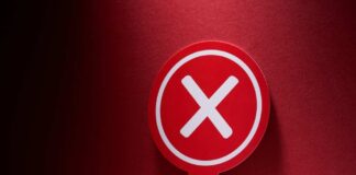Red sign with a white cross symbol on a dark background