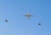 A commercial airplane flying above two military jets in a clear blue sky