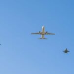 A commercial airplane flying above two military jets in a clear blue sky