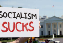 Person holding a protest sign that reads 'SOCIALISM SUCKS' in front of the White House