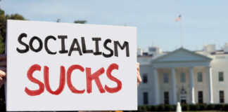 Person holding a protest sign that reads 'SOCIALISM SUCKS' in front of the White House