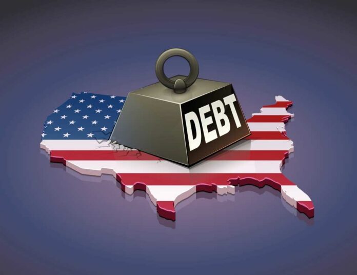 shutterstock_2100595465.jpg A heavy weight labeled 'DEBT' sits on a map of the United States, symbolizing economic challenges.