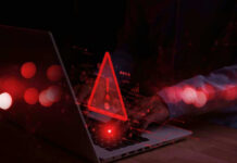 Warning symbol over laptop with user.