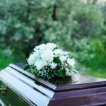 A casket adorned with white flowers in a natural setting