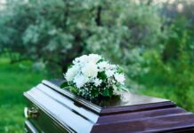 A casket adorned with white flowers in a natural setting