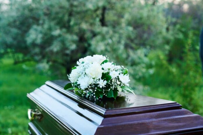 A casket adorned with white flowers in a natural setting