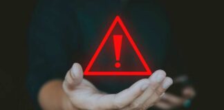 A hand holding a red warning triangle with an exclamation mark