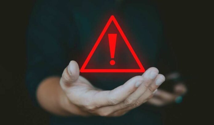 A hand holding a red warning triangle with an exclamation mark