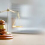 A wooden gavel and scales of justice on a desk