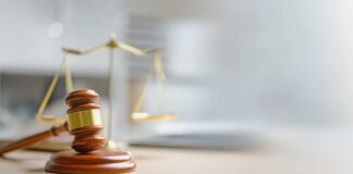 A wooden gavel and scales of justice on a desk