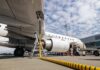 An airplane being fueled at an airport with a visible jet engine