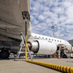 An airplane being fueled at an airport with a visible jet engine