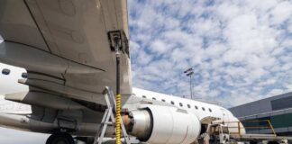 An airplane being fueled at an airport with a visible jet engine
