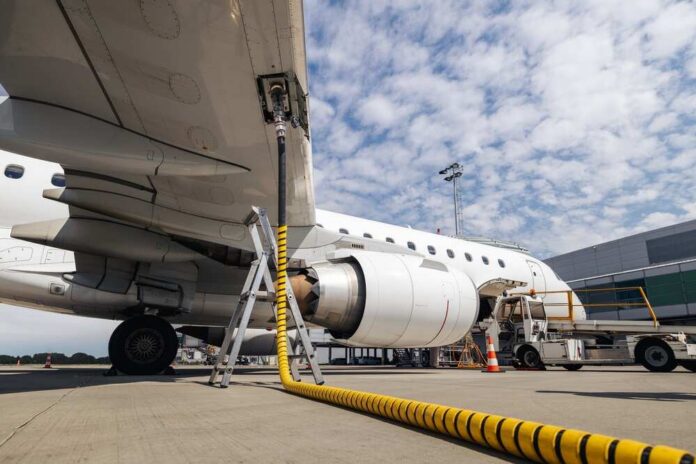An airplane being fueled at an airport with a visible jet engine