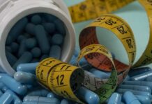 Blue capsules spilled from a white bottle alongside measuring tapes