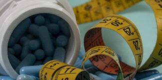 Blue capsules spilled from a white bottle alongside measuring tapes