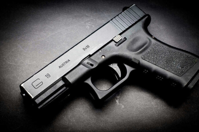 Black Glock 19 pistol on a dark surface.