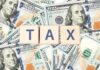 Gas Tax Holiday: Trump’s Latest Push Wooden blocks spelling 'TAX' on a background of U.S. dollar bills