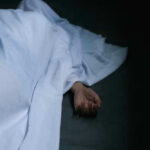BOXCAR HORROR: Six Dead Hand emerging from under white sheet on dark surface.