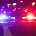 Police officer and vehicle with flashing lights.