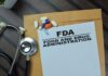 FDA SLAMS Dog Food Brand – Deadly Pathogens Found! FDA document with pills and a stethoscope on a wooden surface