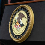 DOJ Drops Bombshell: Billionaire Bribery Case Vanishes! Department of Justice seal on a podium.