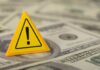 Trump’s Bold Move: New Fed Boss Talks Reform A yellow warning sign placed on a pile of dollar bills