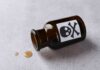 Amber glass bottle labeled with a skull and crossbones, tipped over with liquid spilled