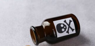 Amber glass bottle labeled with a skull and crossbones, tipped over with liquid spilled