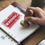 Dangerous Product Recall – Handle May DETACH and Cause Burns! A hand applying a warning stamp on a document
